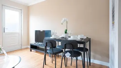 a black dining room table with chairs and a tv at Forbes House in Glasgow