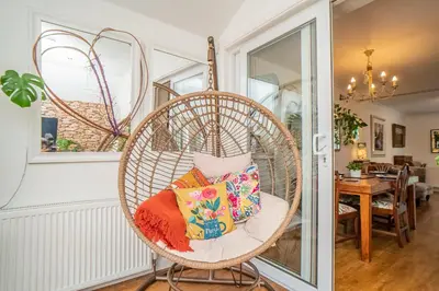 a wicker chair with pillows in a living room at Edinburgh Pad in Edinburgh