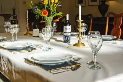 a table with plates and glasses on a white table cloth at Achranich House in Lochaline