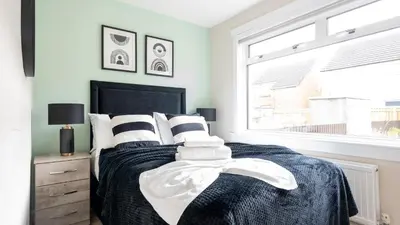 a bedroom with a bed with black and white pillows at Tummel Place in Grangemouth