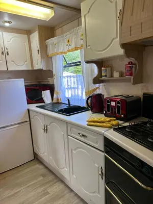 a kitchen with white cabinets and a stove top oven at 27 Glenfinart Caravan Park in Dunoon