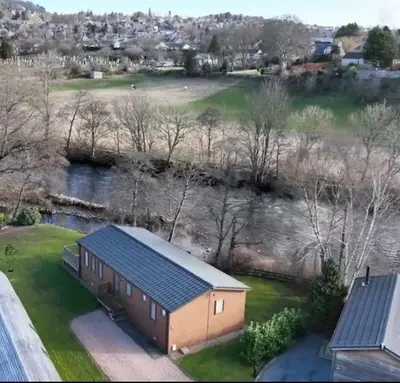 a house with a blue roof and a field at Luxurious Riverside Lodge - 'The Ardle' in Crieff