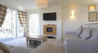 a living room with a couch and a tv at Luxurious Riverside Lodge - 'The Ardle' in Crieff