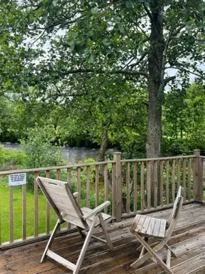 two chairs sitting on a deck near a fence at Luxurious Riverside Lodge - 'The Ardle' in Crieff