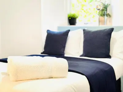 a white bed with blue and white pillows on it at Cosy City Centre Apartment in Edinburgh