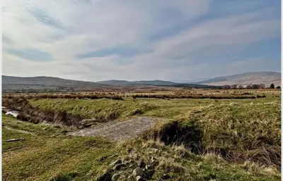 a grassy field with mountains in the distance at Granite House in Carsphairn