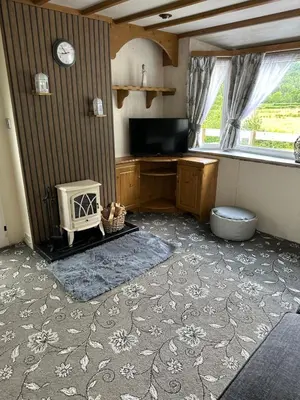 a living room with a tv and a desk and a window at 77 Glenfinart Caravan Park in Dunoon