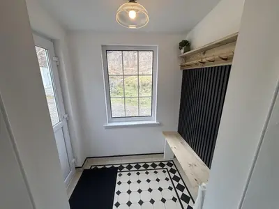 a hallway with a window and a black and white floor at Altchourunn Cottage in Acharra