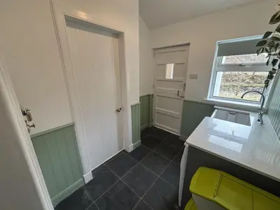 a bathroom with green and white walls and a door at Altchourunn Cottage in Acharra