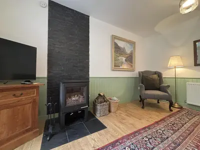a living room with a fireplace and a chair and a television at Altchourunn Cottage in Acharra