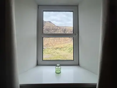 a window with a vase sitting on a window sill at Altchourunn Cottage in Acharra