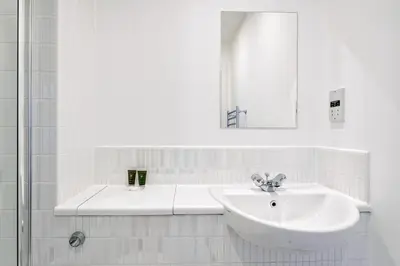 a white bathroom with a sink and a mirror at Argyle Street Apartments in Glasgow