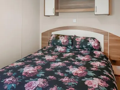 a bed with a black and pink floral bedspread at Platinum in Newton Stewart