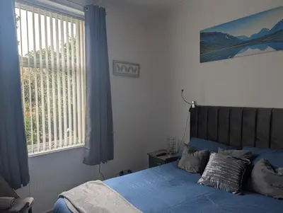 a bedroom with a bed with blue sheets and a window at Largs seaside retreat in Largs