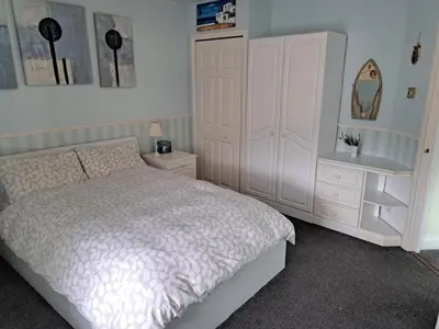 a bedroom with a bed and a dresser and a mirror at Historic central apartment in Castlehill Mansions in Campbeltown
