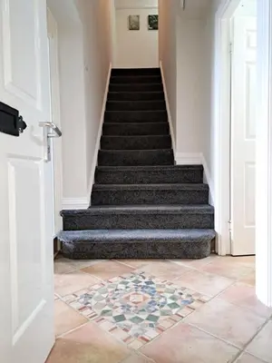 a hallway with stairs with a tile floor at Historic central apartment in Castlehill Mansions in Campbeltown