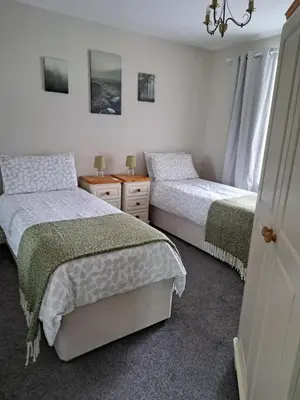 a bedroom with two beds and a chandelier at Historic central apartment in Castlehill Mansions in Campbeltown