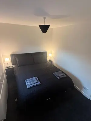 a bedroom with a bed with two lamps on it at Home Comfort Prestwick in Prestwick