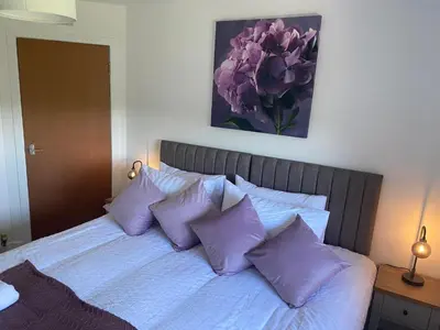 a bed with purple pillows and a painting on the wall at Glen Cannich - Top Location, 2BR Accessible apt in Inverkeithing