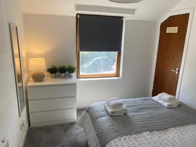 a bedroom with a bed and a window with towels on it at Glen Cannich - Top Location, 2BR Accessible apt in Inverkeithing