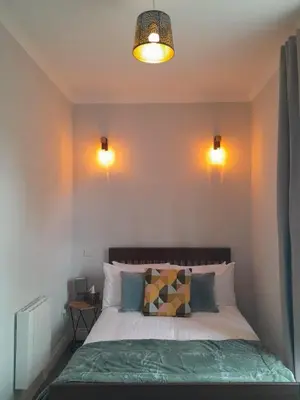 a bedroom with a bed with two lights on the wall at Outlander 4 Apartment Doune in Stirling