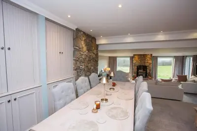 a dining room with a table and a living room at 5 Bed Family Home Lochwinnoch in Lochwinnoch