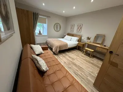 a bedroom with a bed and a couch in a room at BOFA Snug Apartment in Bridge of Allan