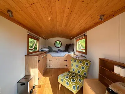 a bedroom in a tiny house with a bed and a chair at The Shepherd's Hut in Craighouse