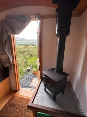 a wood stove in a room with a window at The Shepherd's Hut in Craighouse