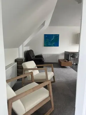 a living room with two chairs and a table at Upper Mill Apartment in Newmilns