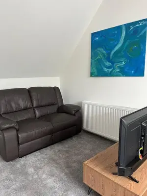 a living room with a brown couch and a tv at Upper Mill Apartment in Newmilns