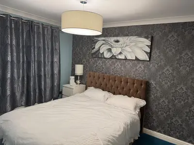 a bedroom with a large white bed with a flower painting at Glasgow 3 bed Guest House in Glasgow
