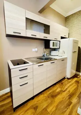 a kitchen with white cabinets and a sink and a refrigerator at Isle Be Back-Ground Floor Flat in Millport