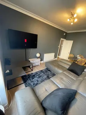 a living room with two couches and a flat screen tv at Fountain park get away one bedroom in a 2 bedroom apartment in Edinburgh