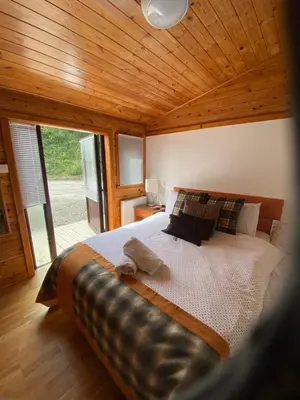a bedroom with a large bed with a large window at Rowardennan Rooms in the lodge Lodge no 2 in Rowardennan