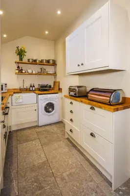 a kitchen with white cabinets and a washer and dryer at Craigendarroch No 2 in Acharn