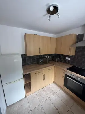 a kitchen with wooden cabinets and a white refrigerator at City Centre 2 Bed Apartment in Glasgow