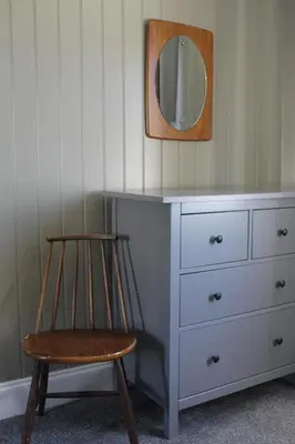 a chair sitting next to a dresser with a mirror at Fortingall Cottage - Dalmally in Dalmally