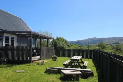 a picnic table in the grass next to a fence at Fortingall Cottage - Dalmally in Dalmally