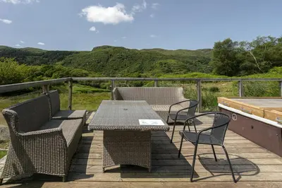 a patio with a table and chairs on a deck at Dalnahua on 'The Secret Coast'
