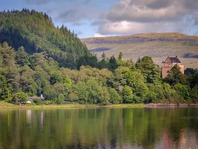 a building sitting on the side of a lake at Castle Cottage No 2 in Acharn