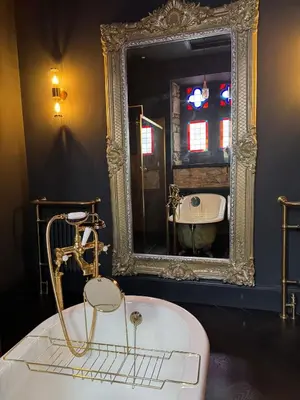 a bathroom with a tub and a large mirror at The Old Church Isle of Bute in Port Bannatyne