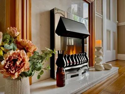 a fireplace in a living room with flowers on a counter at Hide-a-While in Rothesay