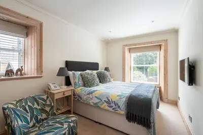 a bedroom with a bed and a chair and a window at Little Juniper Lodge in Edinburgh
