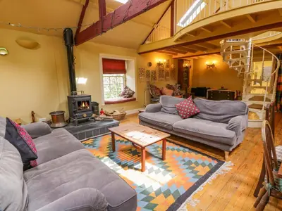 a living room with couches and a wood stove at Townhead of Auchenbainzie in Thornhill