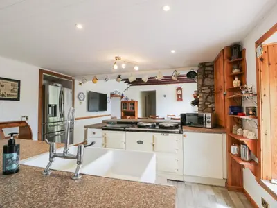 a kitchen with white cabinets and a counter top at Marshill Farm House in Lanark
