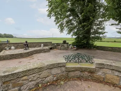 a bench sitting on a stone wall with a tree at Marshill Farm House in Lanark