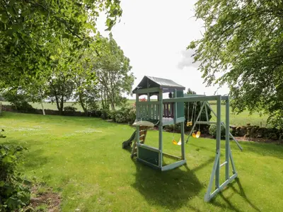 a playground in a yard with a swing at Marshill Farm House in Lanark
