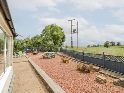 a patio with a picnic table and a fence at Marshill Farm House in Lanark