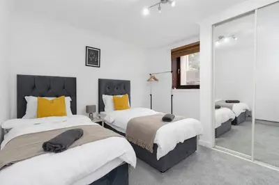 a bedroom with three beds and a mirror at Free Parking - Sleeps 6 - Central - New Interior in Greenock
